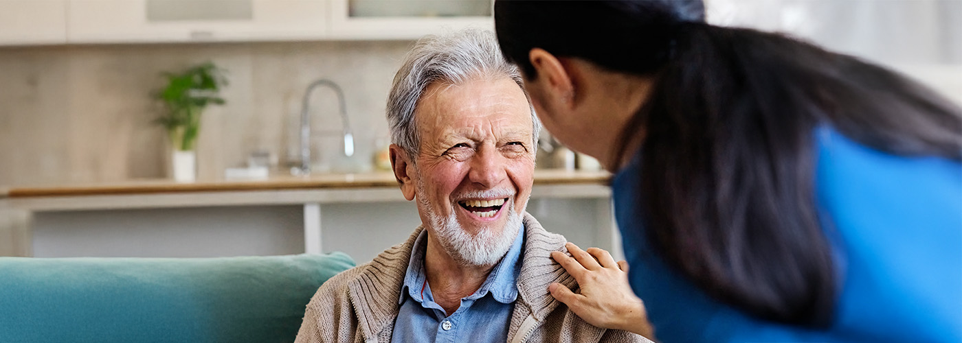 Senior man smiles at female caregiver
