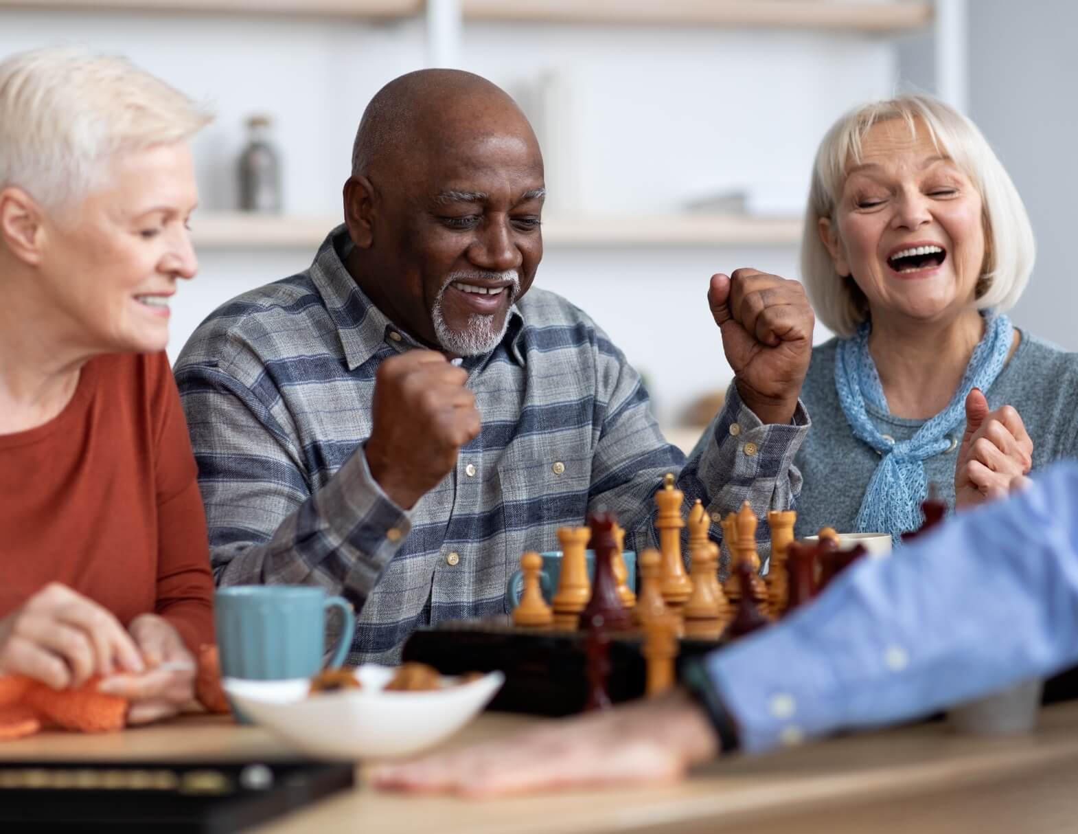 Seniors enjoying a chess game at a community center with joyful expressions.