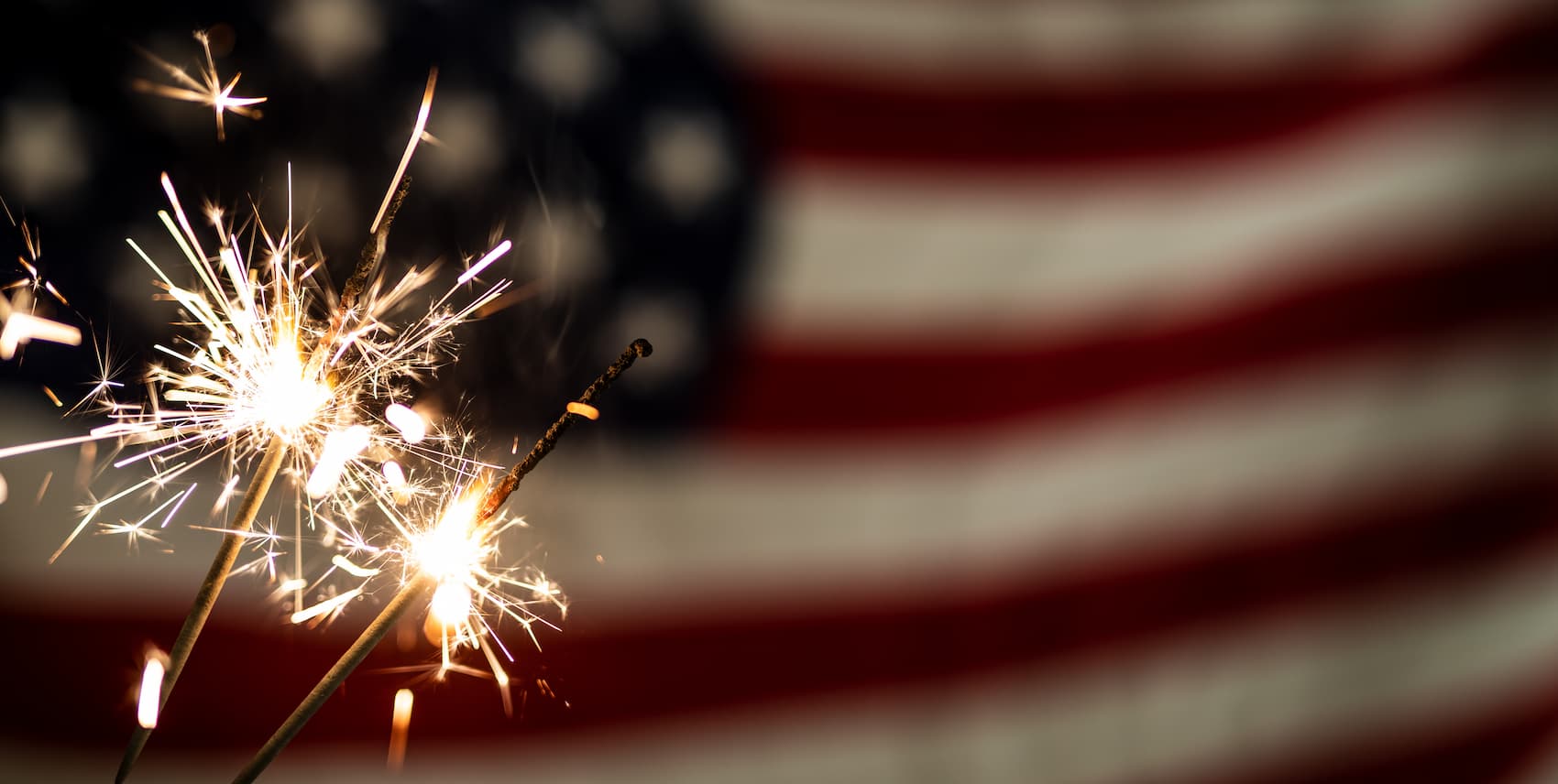 Lit sparklers and American flag in the background