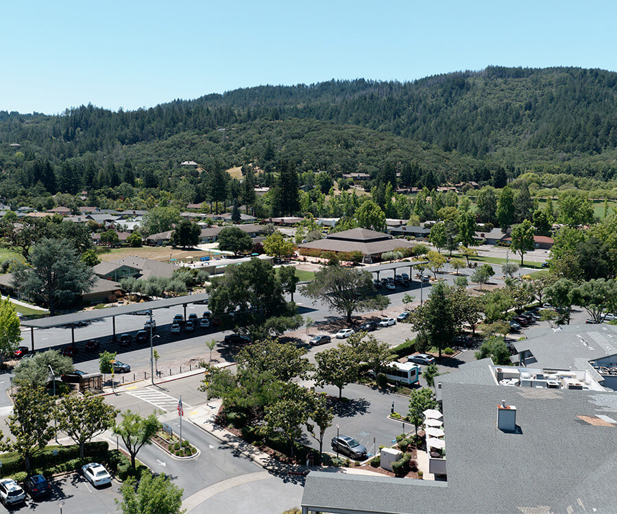 Aerial view of a senior living community surrounded by lush greenery and forested hills.