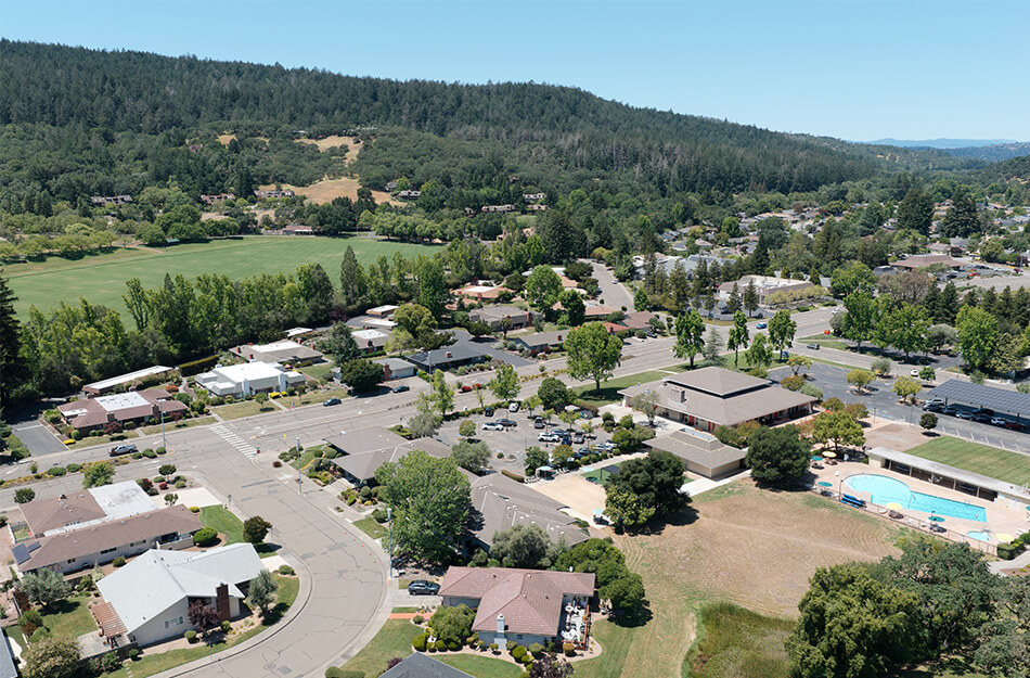 Aerial view of a senior living community with units, main building, and nearby greenery.