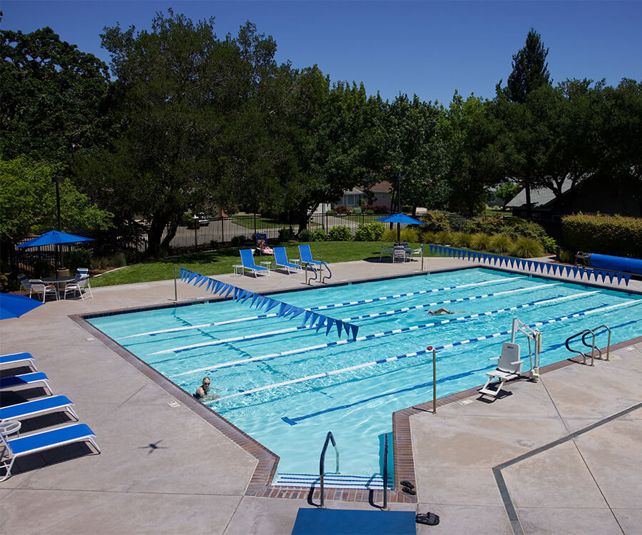 Swimming pool at a senior living community with lounge chairs and umbrellas.