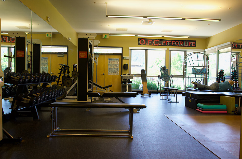 Fitness center with workout equipment and large windows at a senior living community.