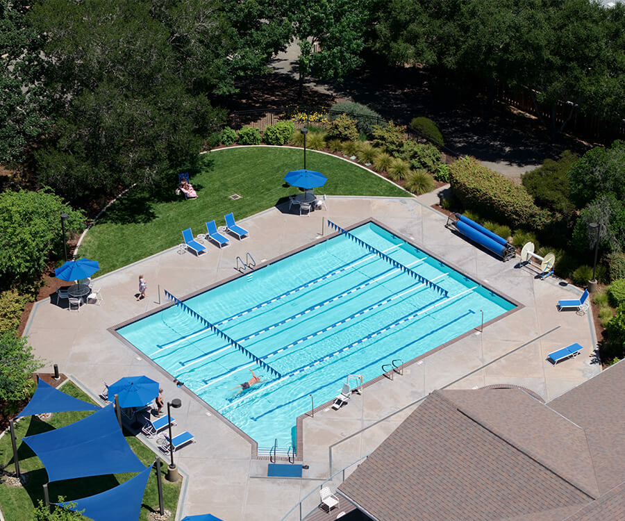 Aerial view of a senior living pool area with lounge chairs and umbrellas.