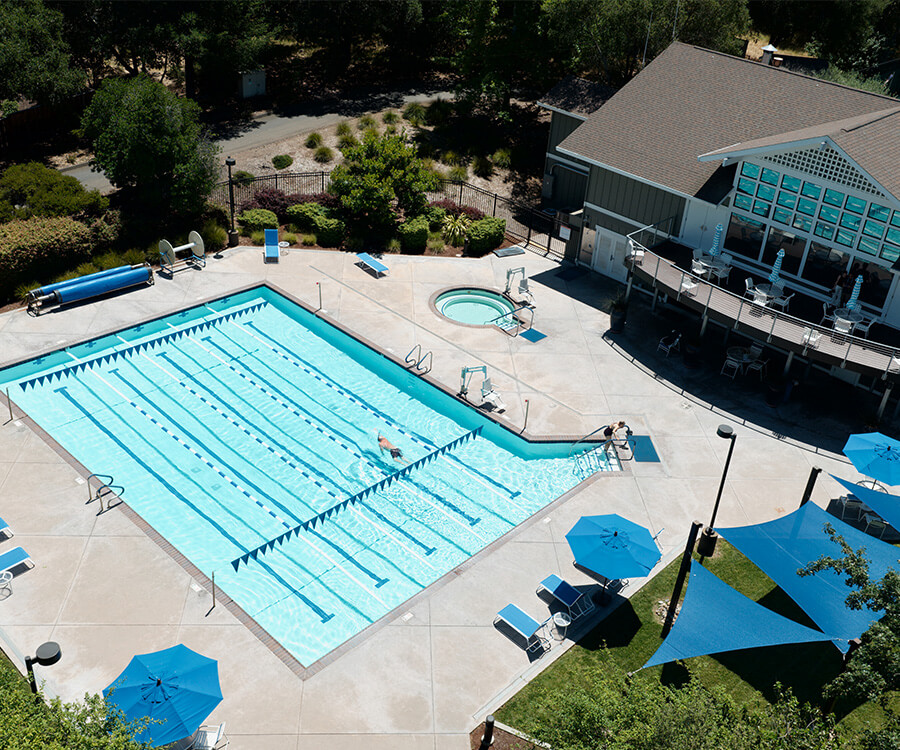 Aerial view of a pool and spa area in a senior living community with patio seating.
