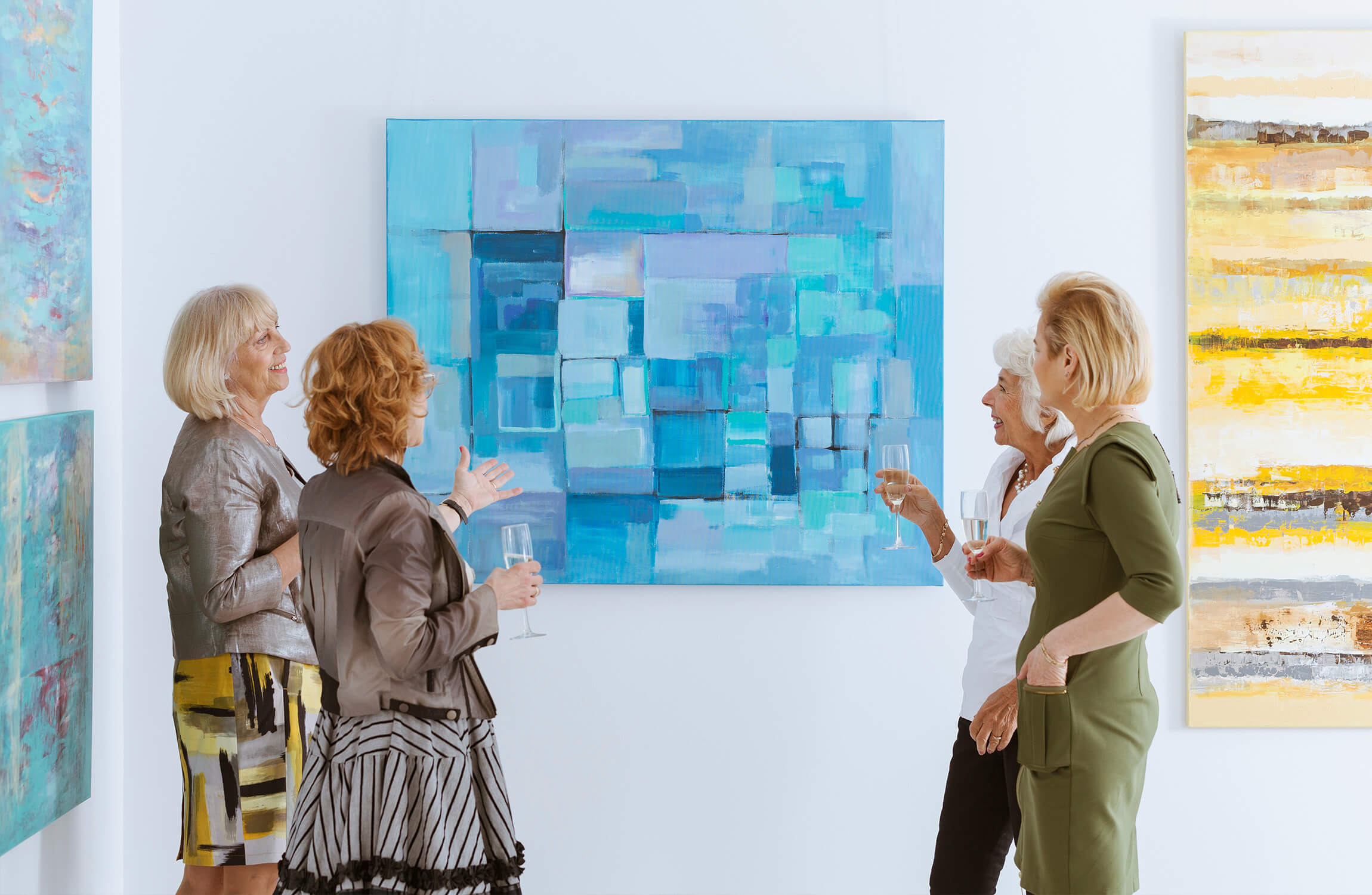 Four senior women discussing painting in art gallery